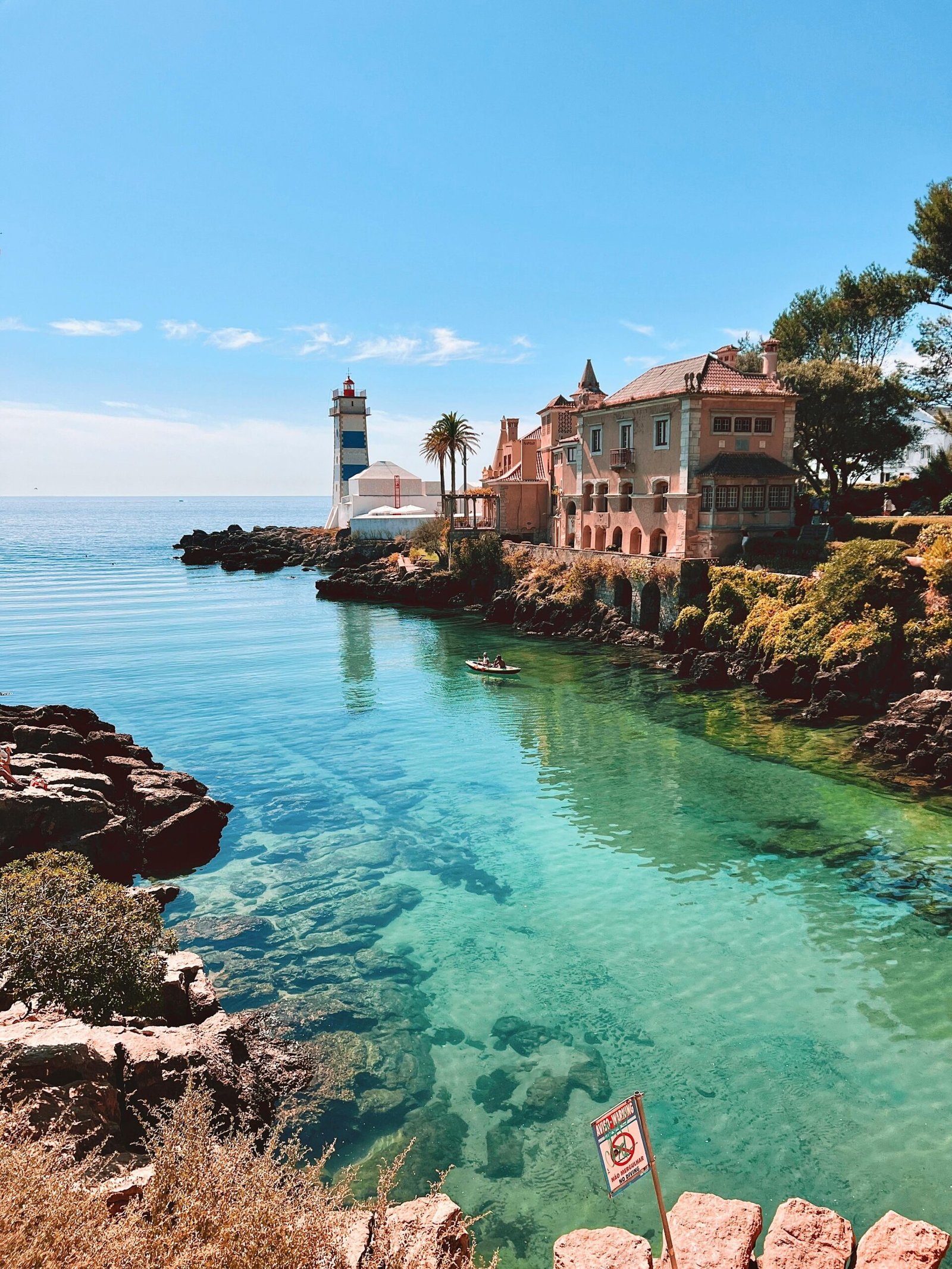 Picturesque Cascais coastline with a lighthouse and clear blue waters.